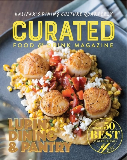 Magazine cover featuring a dish with scallops and vegetables, titled 'Curated Food & Drink Magazine' with 'Lupin Dining & Pantry' on a dark background.