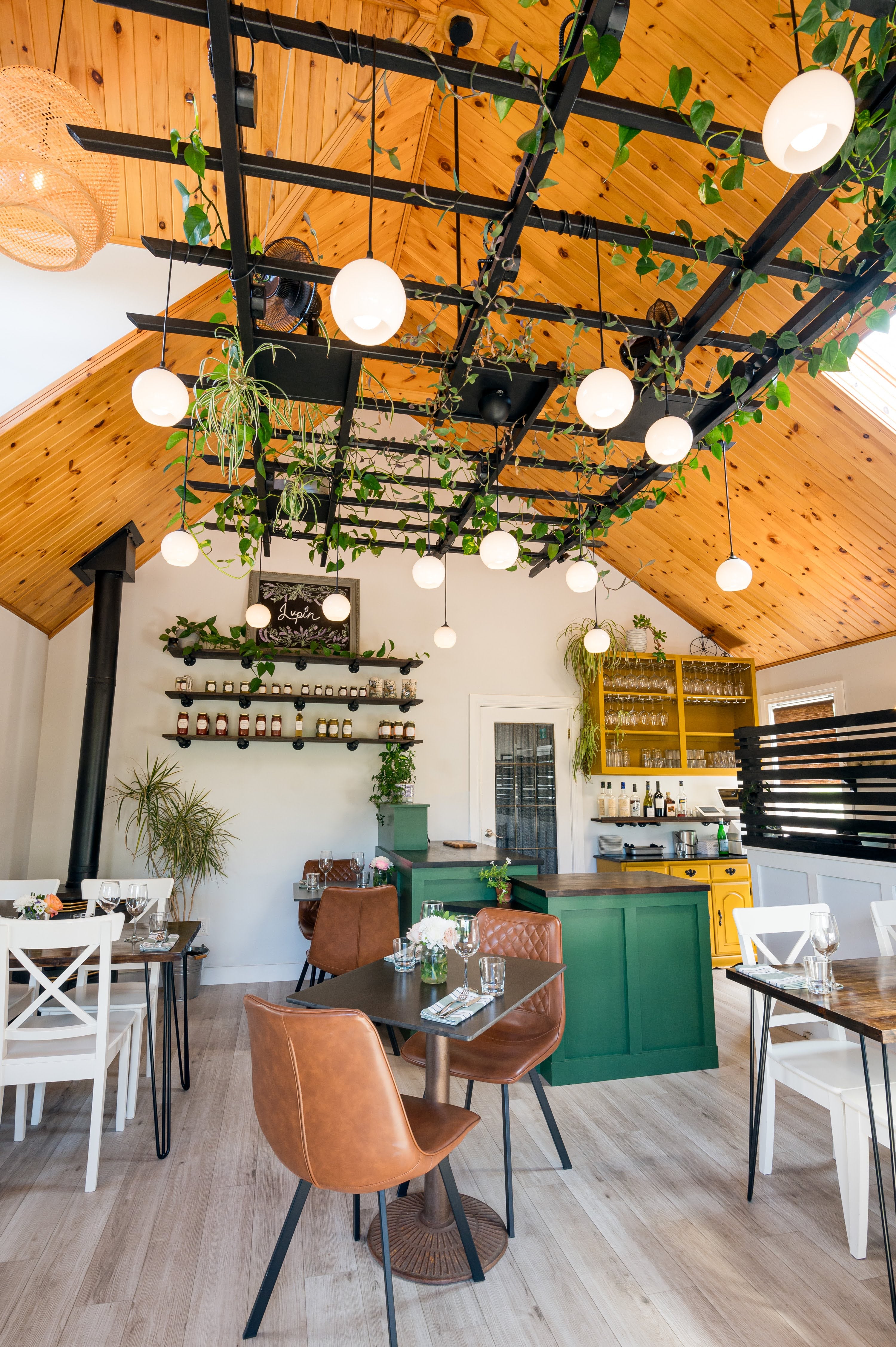 Modern dining room with wooden ceiling, pendant lights, and green island.