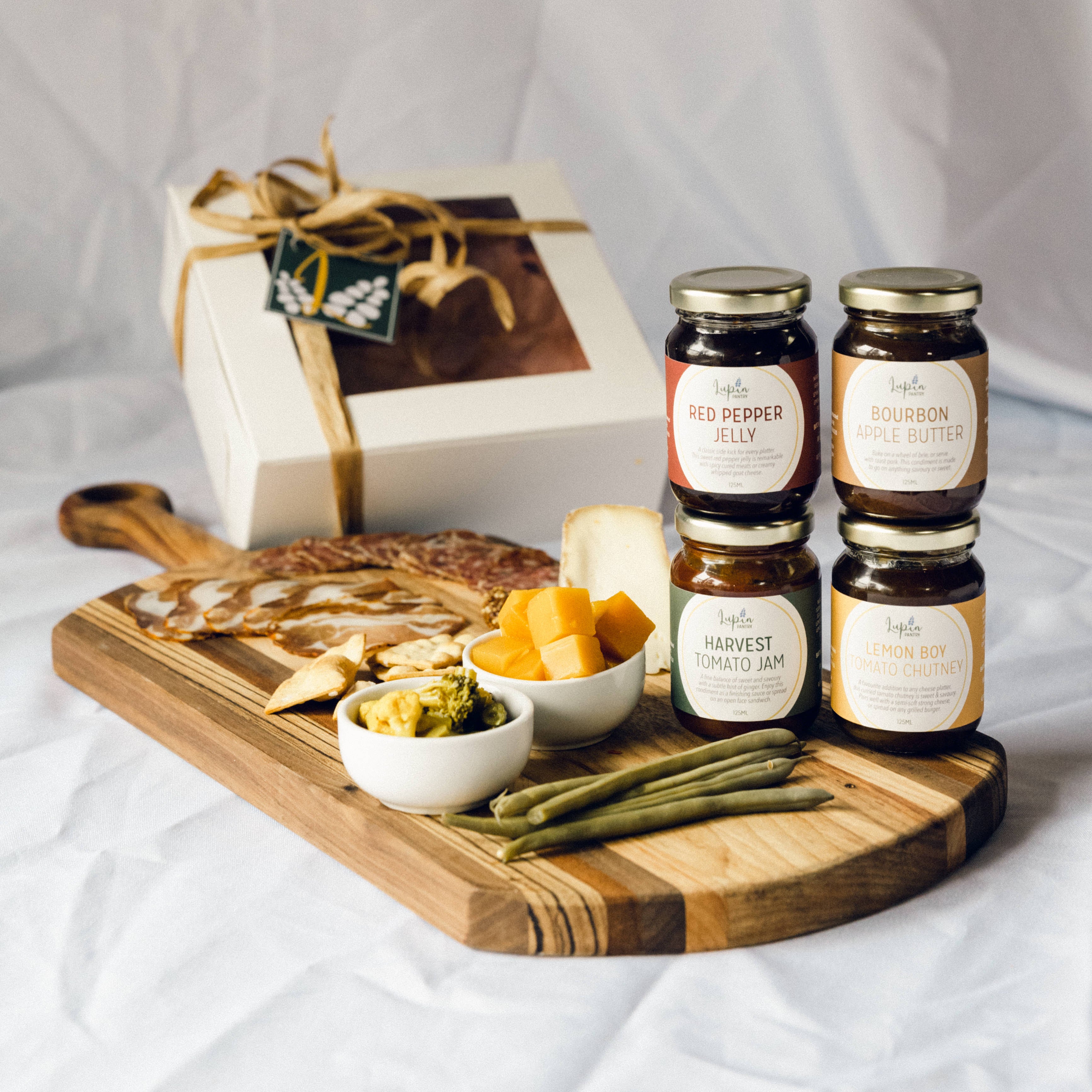 cutting board with various meat and cheese and a selection of jarred jelly