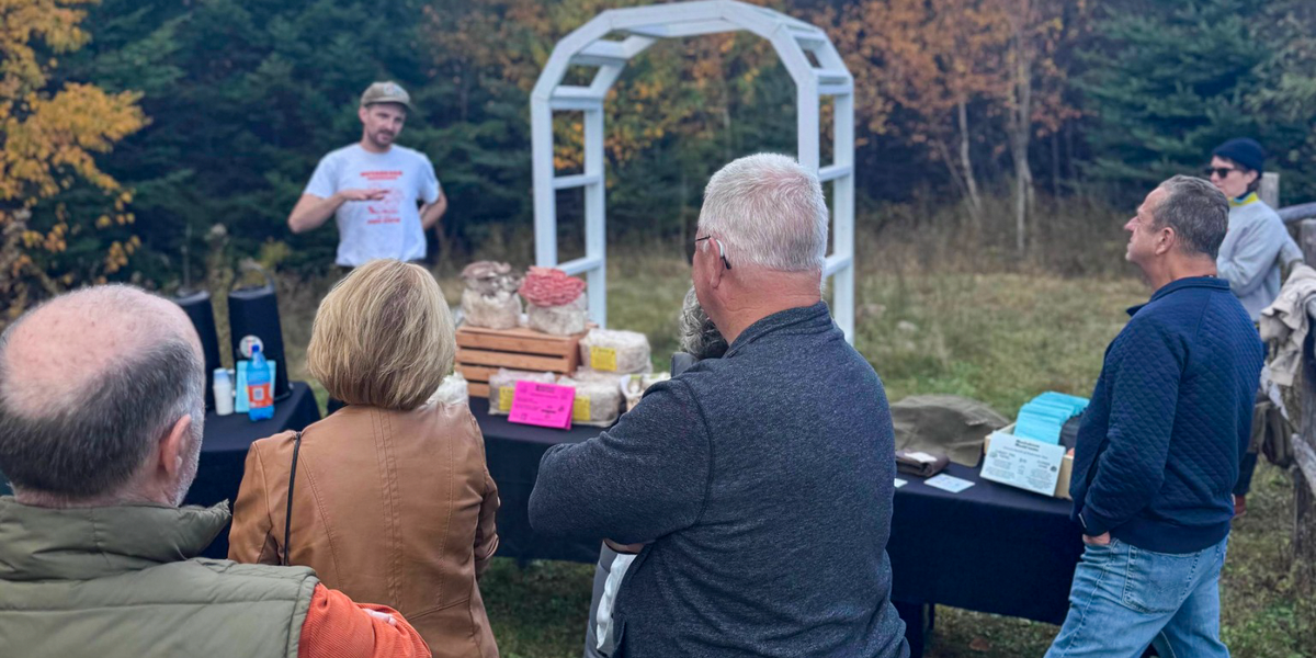 Guests listening to a mushroom grower beside a display of cultivated mushrooms at the Harvest Food Festival.