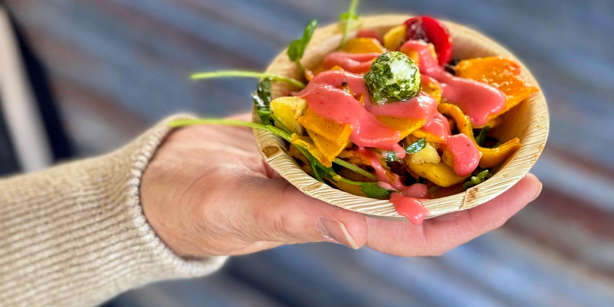 A colourful tasting dish with vegetables, greens and pink sauce, served in a small bowl at Lupin’s Harvest Food Festival.