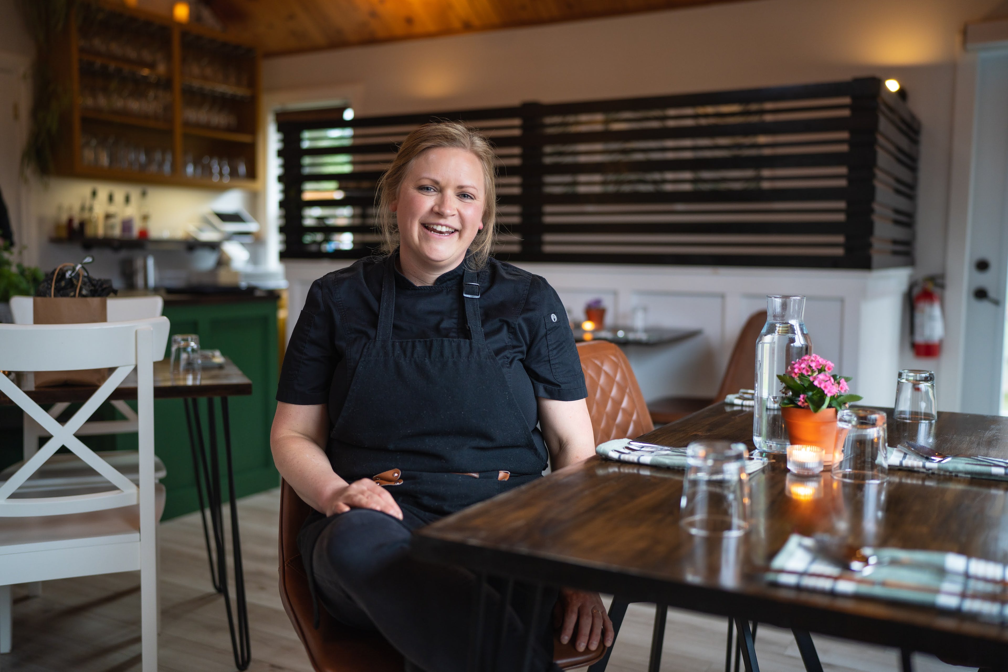 Chef Kim sitting at a table in a restaurant kitchen waring black chef outfit