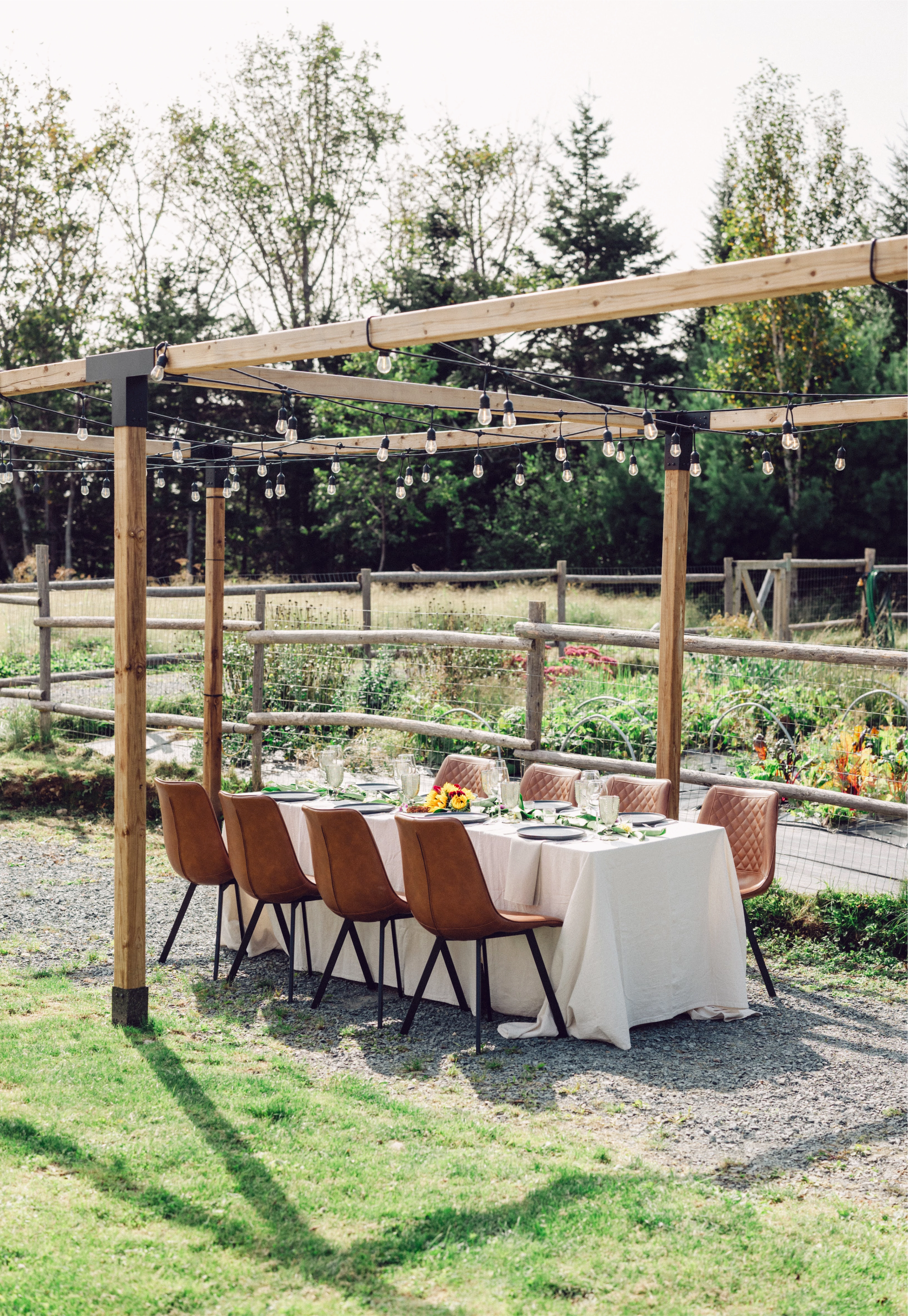 Outdoor setting with a wooden pergola, table set for a meal, and garden view.