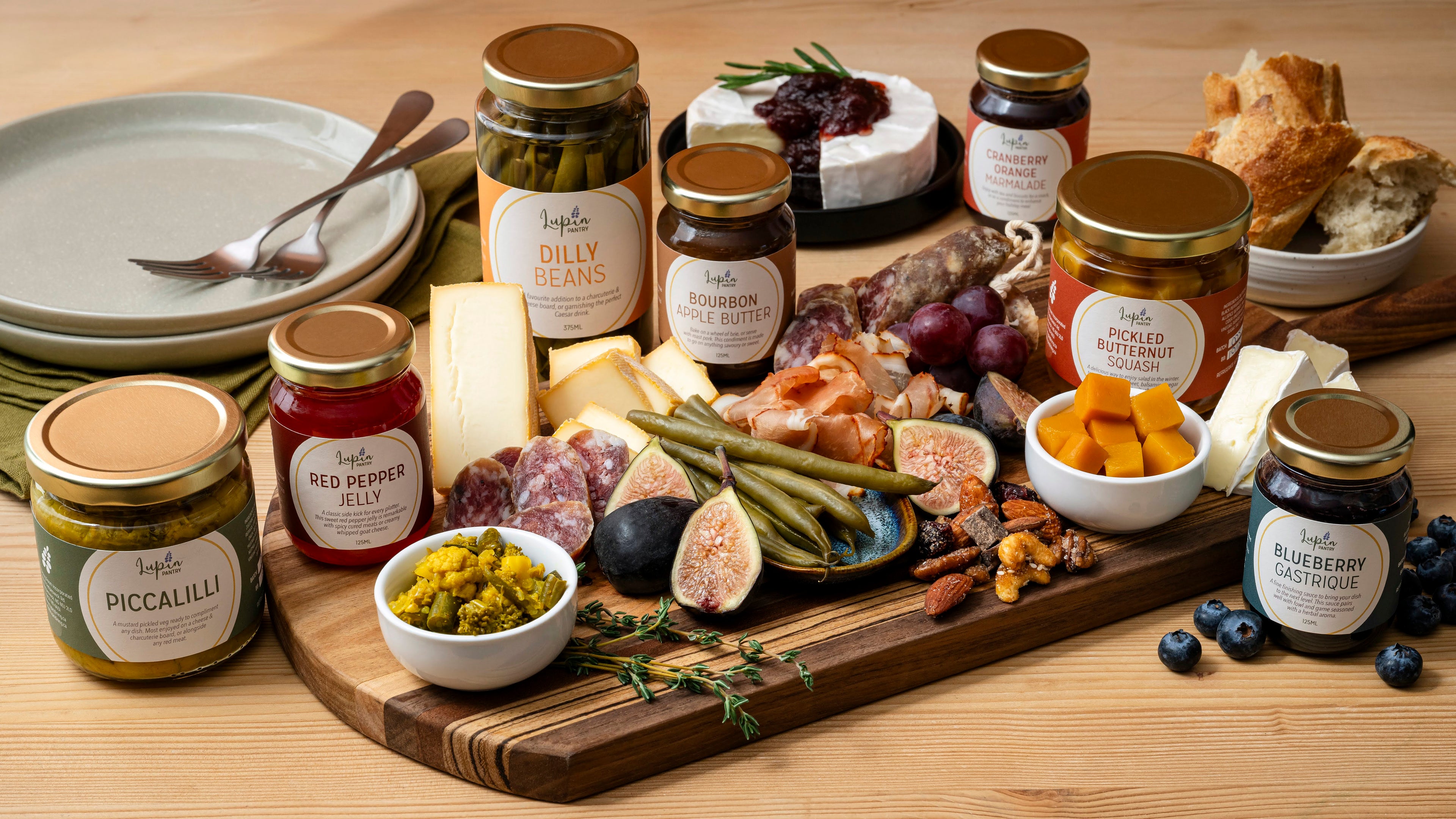 Assorted jars of pickles and cheeses on a wooden board with a variety of food items.